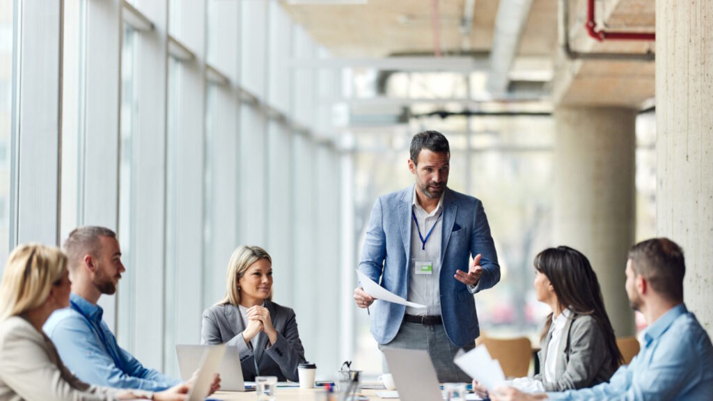 Reunión de trabajo en donde un hombre está de pie hablando